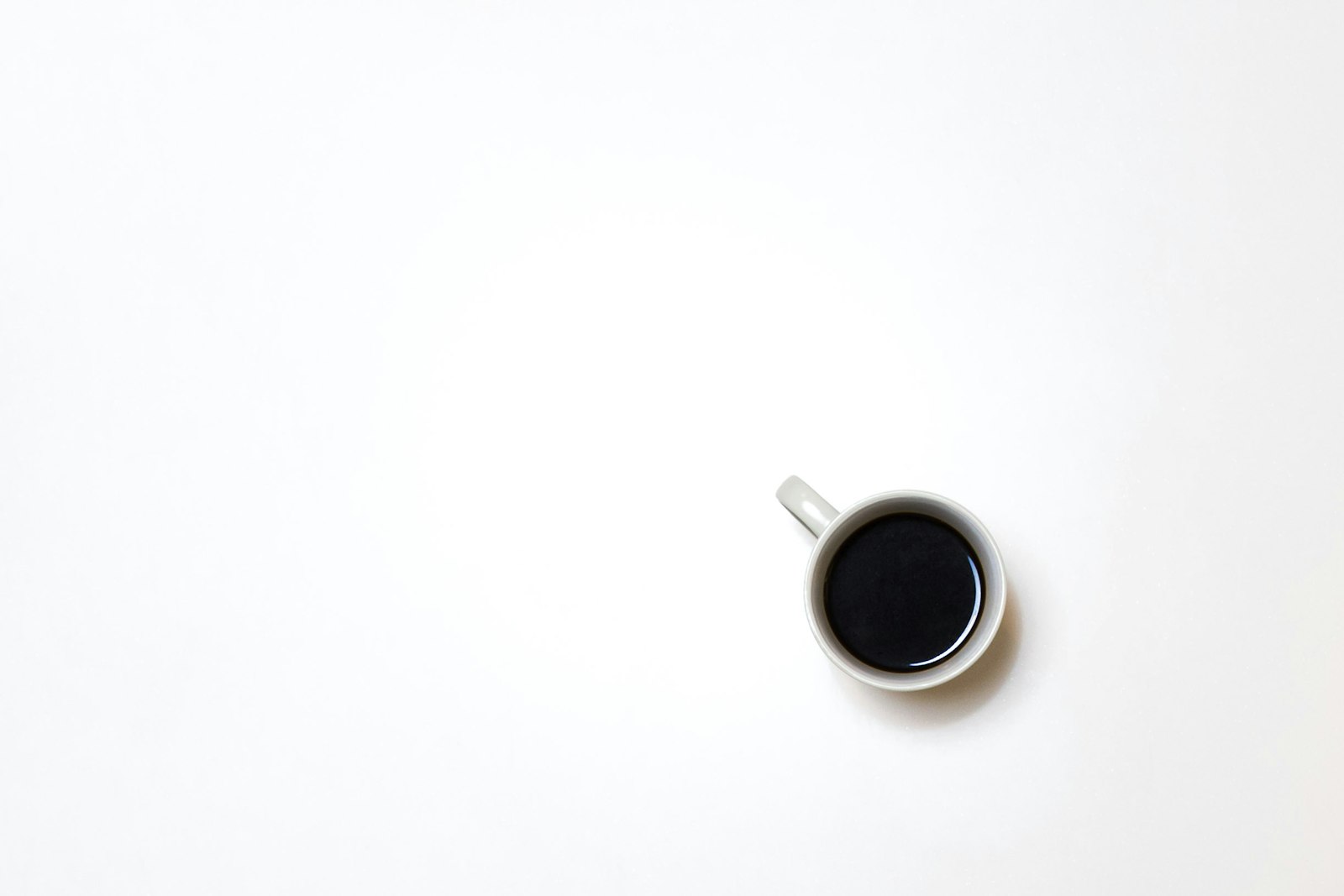 白いテーブルに置かれた、黒いコーヒーの入ったマグカップの俯瞰