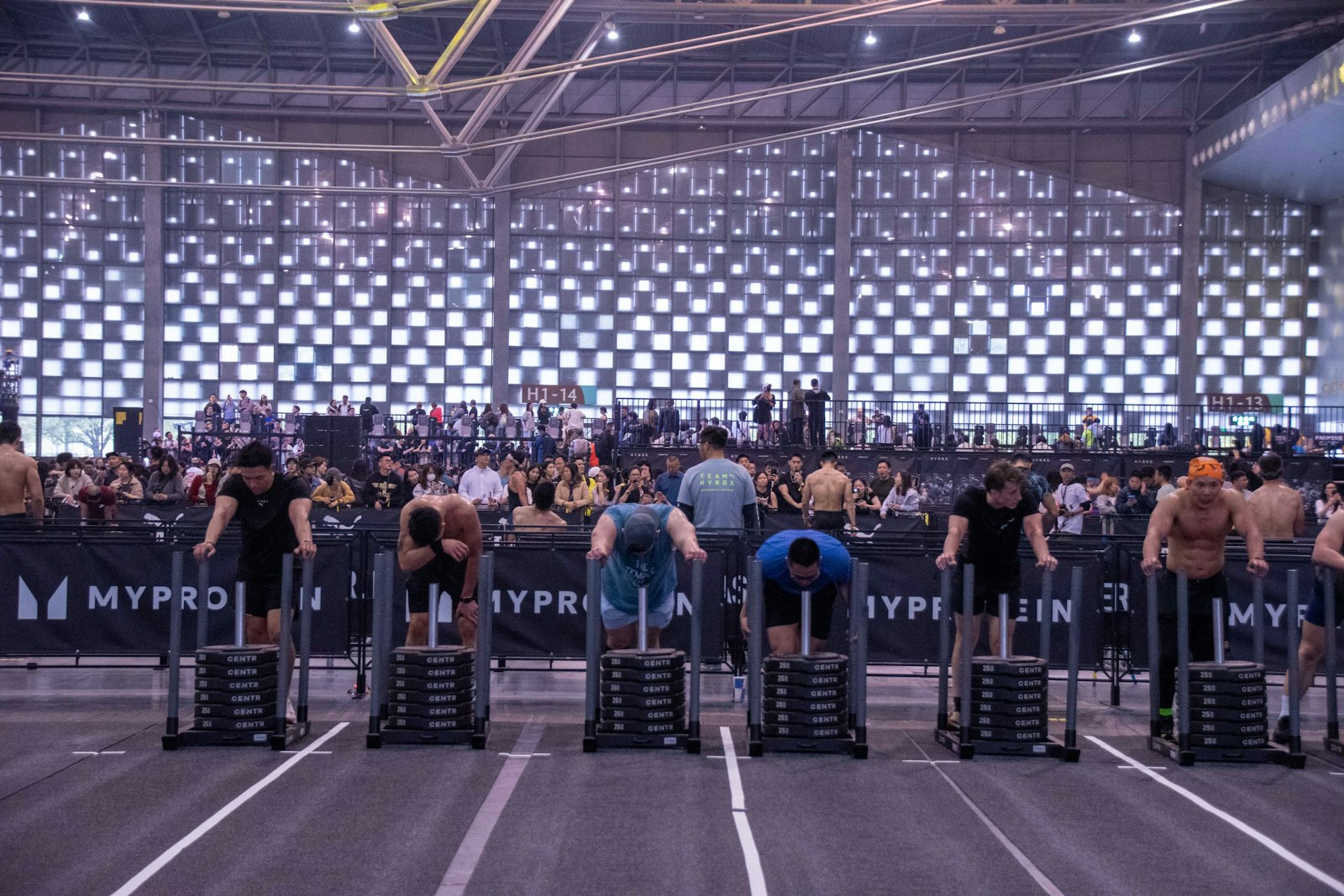 HYROX大会の会場で、ウェイトそりを押して競う選手たち